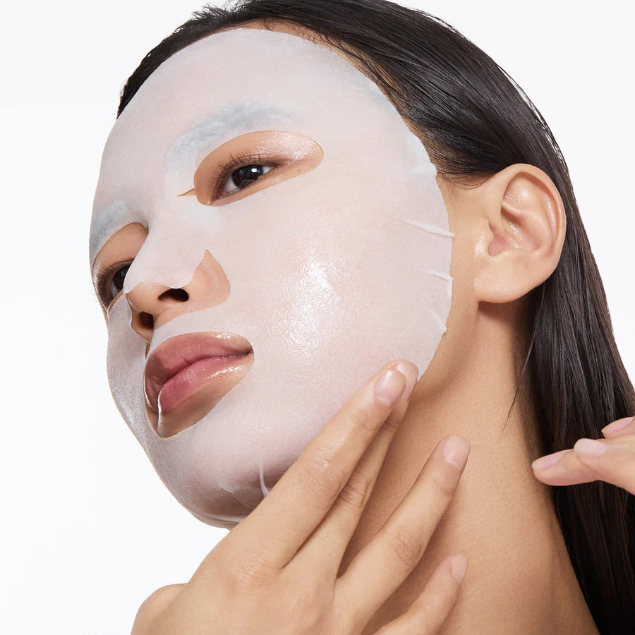 Woman applying Torriden Dive In Low Molecular Hyaluronic Acid Mask with one hand on a white background